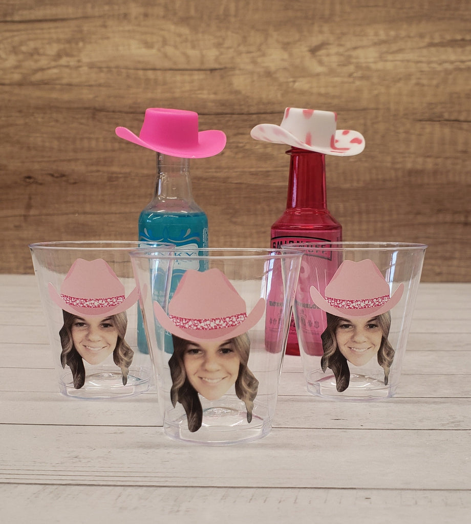 Coastal cowgirl themed party decorations including shot glasses with face and pink cowgirl hat