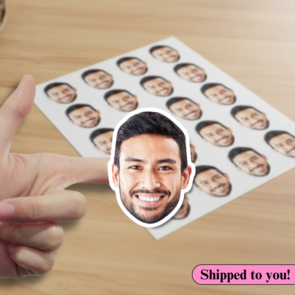 Hand holding a cutout of a smiling person's face with a sheet of similar cutouts on a wooden surface.