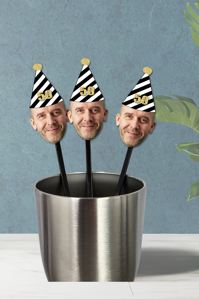 face drink stirrers with a black and white party hat on top
